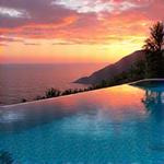 Breathtaking infinity pool overlooking a coastline at sunset.
